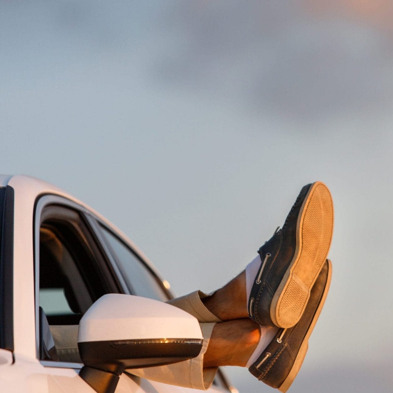 Hombre en coche con los pies fuera de la ventanilla
